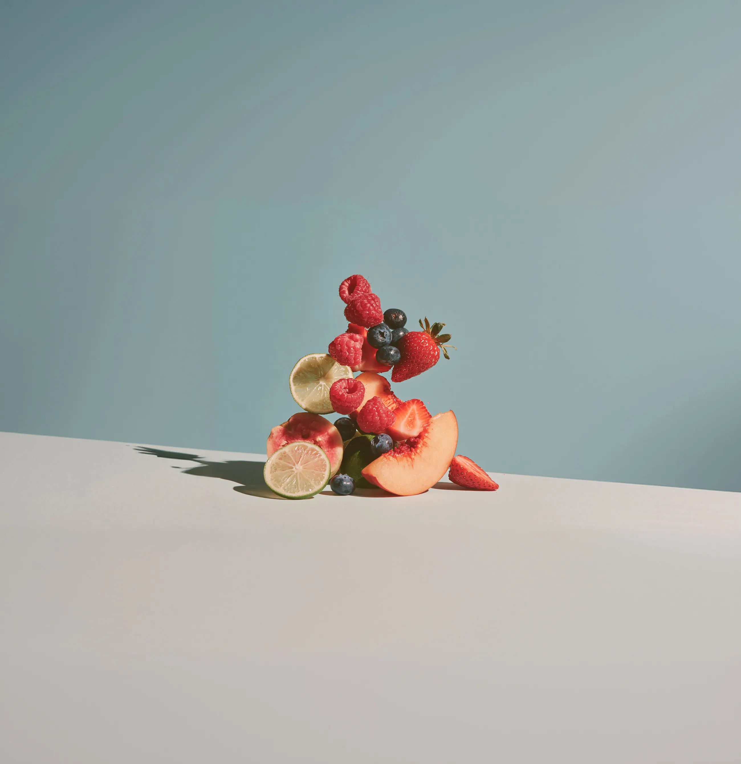 Gestapelte Früchte: Himbeeren, Heidelbeeren, Erdbeeren, Limette und Pfirsich
