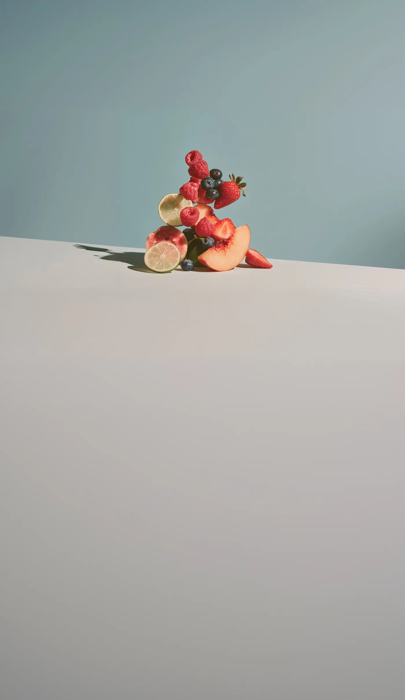 Gestapelte Früchte: Himbeeren, Heidelbeeren, Erdbeeren, Limette und Pfirsich