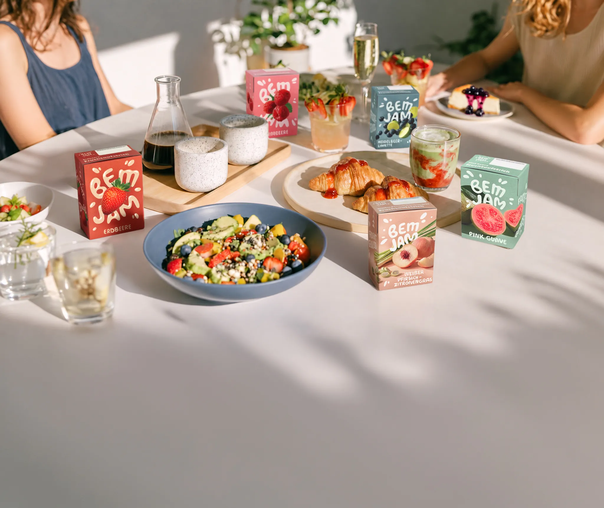 Gedeckter Frühstückstisch mit Bem Jam Packungen, Salat, Croissants und Getränken